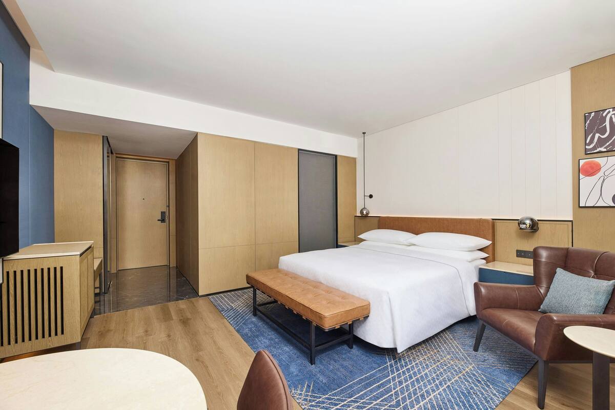 Una habitación de hotel con una cama grande, un escritorio, una banca y una zona de estar.