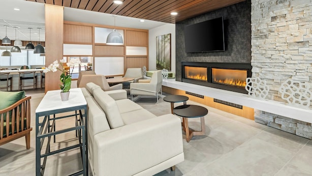 Un soggiorno moderno con camino, soffitto in legno e televisore a parete.
