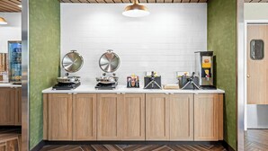 Una cucina con mobili in legno, zoccolo di mattoni bianchi e parete verde decorativa.