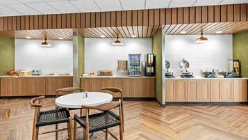Un espace cuisine moderne avec des meubles en bois, une table de salle à manger ronde entourée de chaises et un plancher à motifs en chevrons.