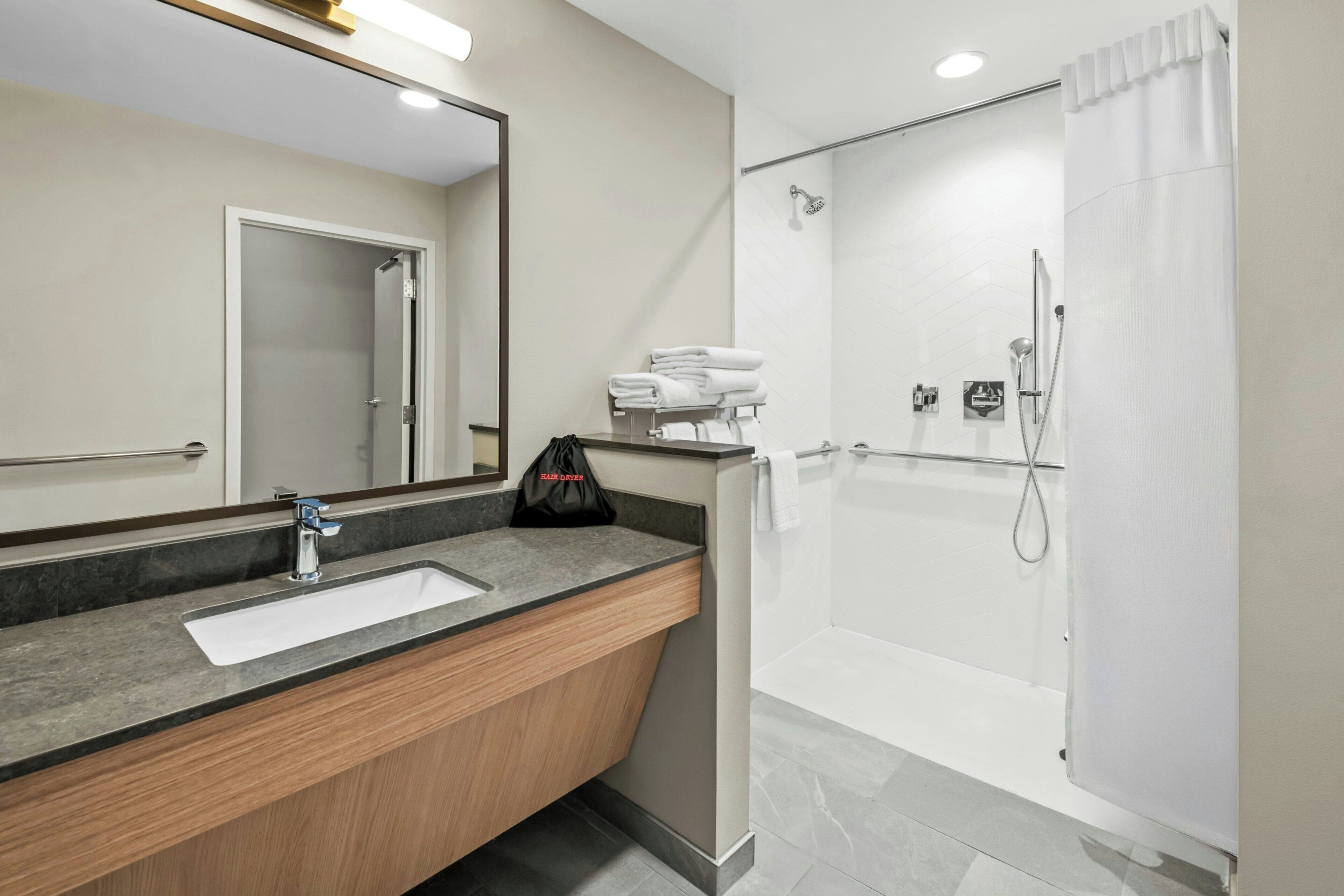 A modern bathroom with a sink, mirror, and shower.