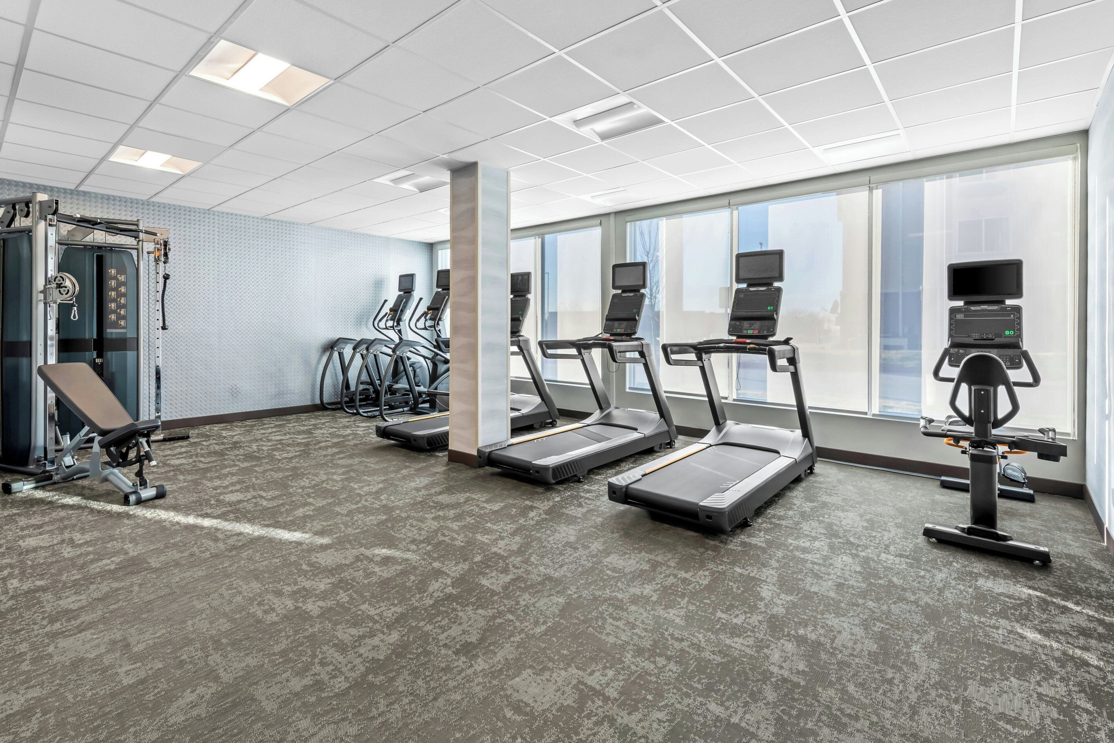 A gym with treadmills, elliptical machines, and weightlifting equipment.