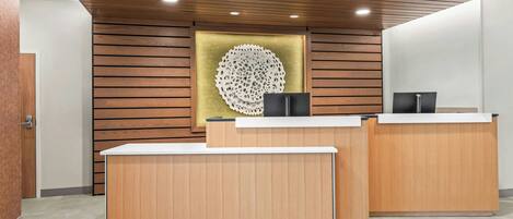 Ein Empfangsschalter mit Holzoptik, eine dekorative Wandgestaltung und ein modernes Deckenleuchtendes Design.