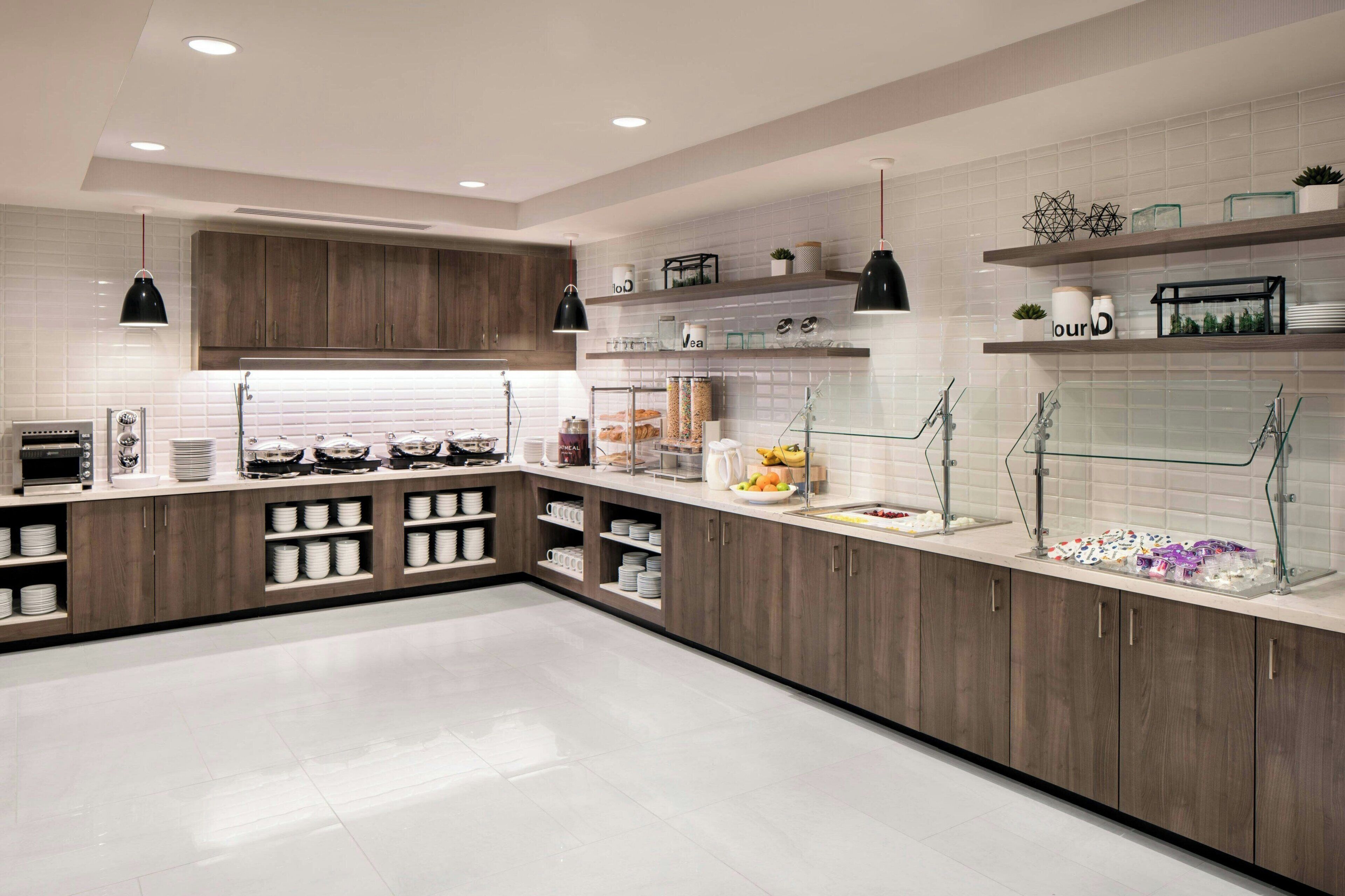 A modern kitchen with wooden cabinets, white countertops, and glass shelving.