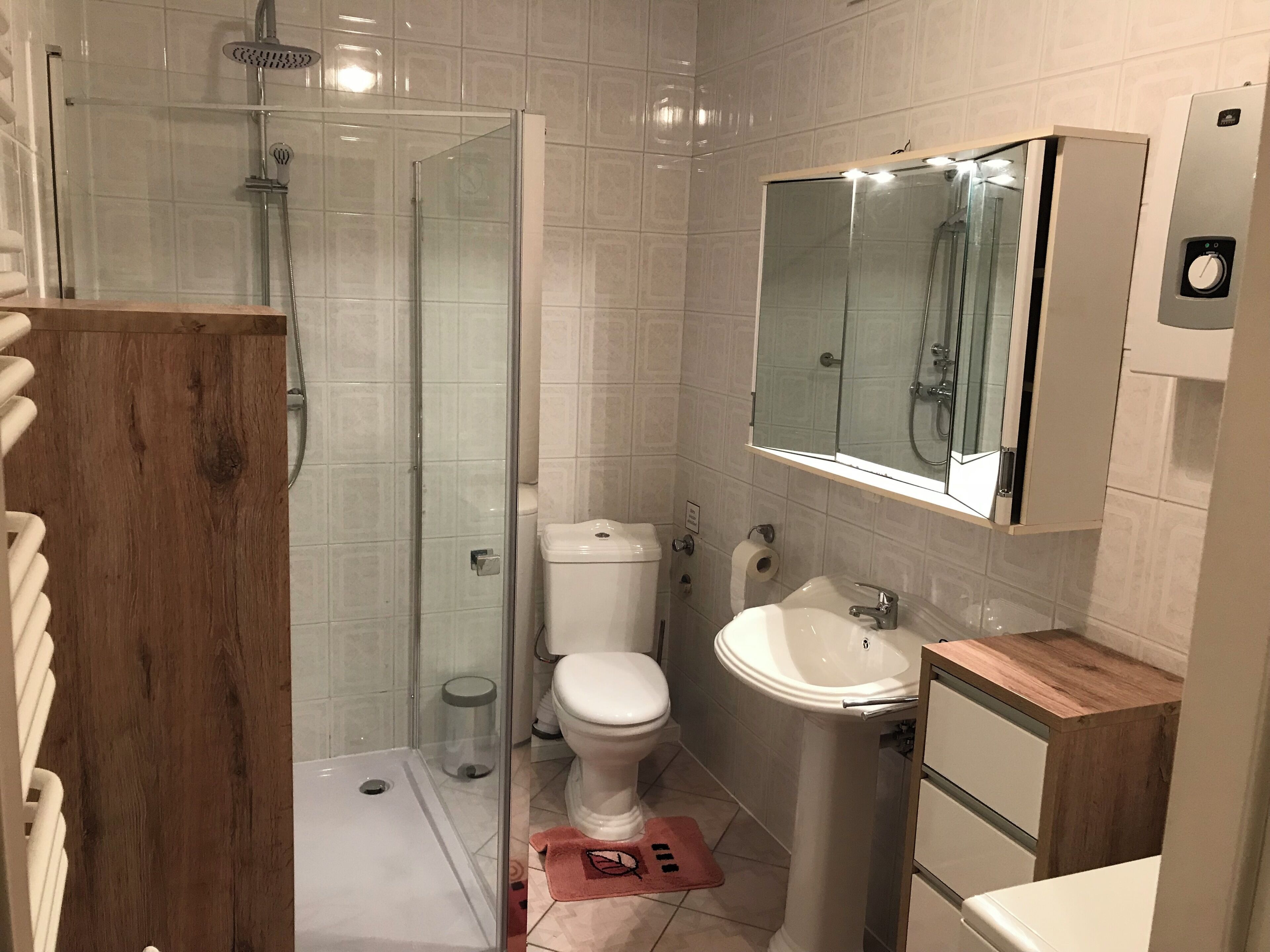 Une salle de bain avec une douche à parois de verre, des toilettes, un lavabo et un miroir au-dessus du lavabo.