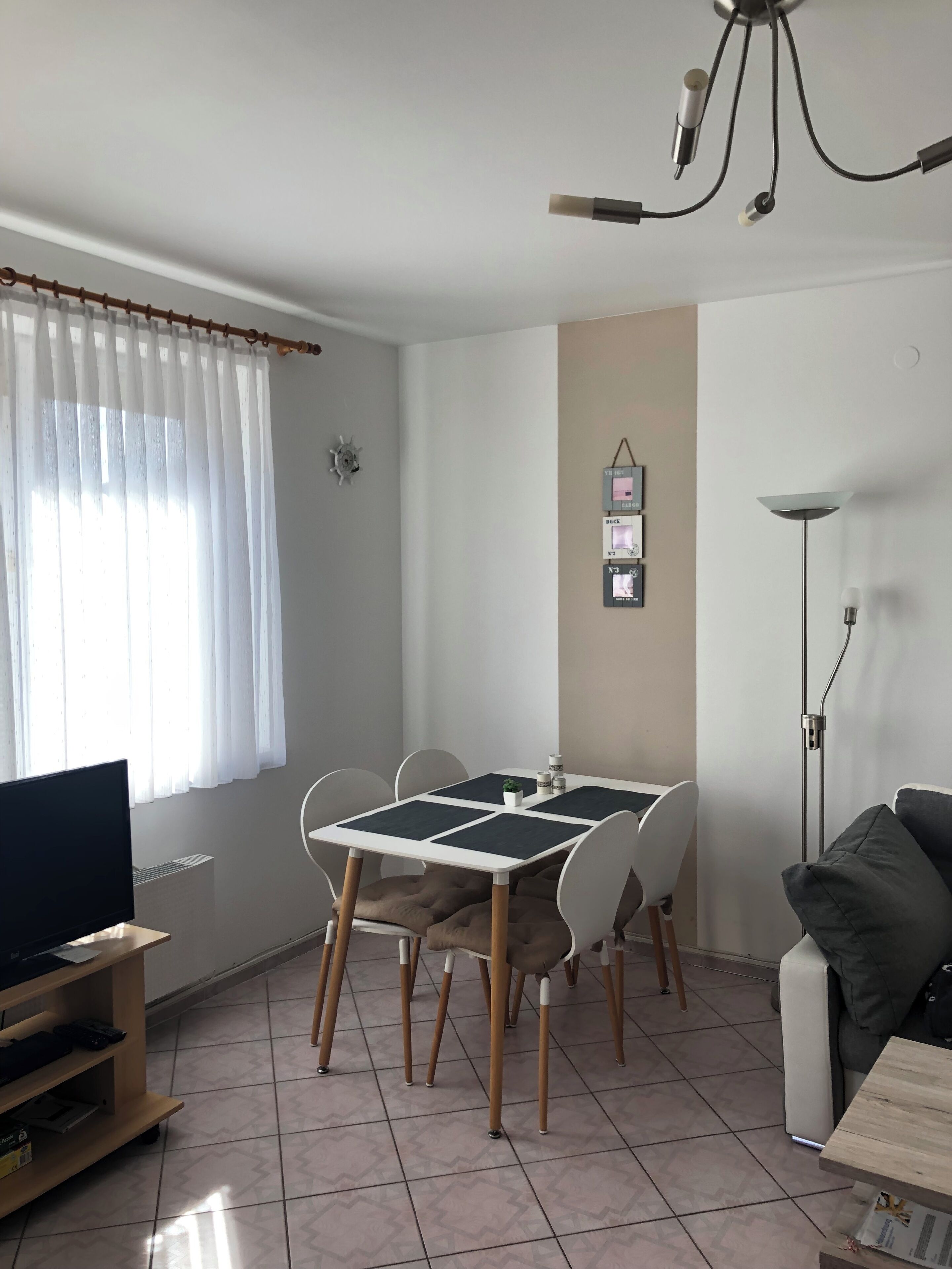 A dining area with a table, chairs, a television, and a floor lamp.