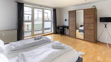 Habitación de hotel con dos camas, un escritorio, un espejo grande y vistas al exterior.