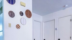 Un espace repas comprenant une table ronde en verre, quatre chaises grises à revêtement en tissu et des pieds en bois.