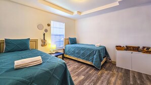 Une chambre avec deux lits, une guitare, une lampe et un meuble contenant des objets décoratifs.