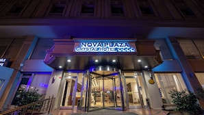 The exterior of the Nova Plaza Crystal Hotel with a prominent illuminated sign, a glass entrance, and a staircase leading to the entrance. - plaza hotel taksim (İstanbul)