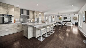 Een moderne keuken met een centraal eiland, roestvrijstalen apparatuur en een eethoek met uitzicht.