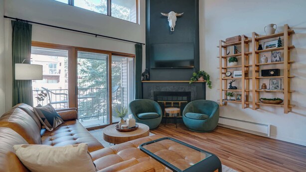 A modern living room with a leather sofa, two green armchairs, a coffee table, and a fireplace. - Warm & Cozy Condo • Prime Angel Fire Location (Angel Fire)