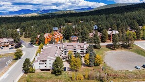 A residential area with multi-story buildings, a parking lot, and a road. - Warm & Cozy Condo • Prime Angel Fire Location (Angel Fire)