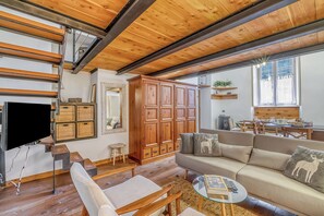 Un salon moderne avec un plafond en bois, une grande armoire, un canapé agrémenté de coussins décoratifs et un téléviseur à écran plat.
