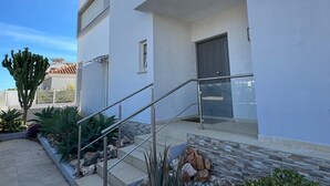 Ein modernes, zweistöckiges Gebäude mit Flachdach, Balkon und einer Treppe zum Eingang.
