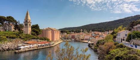 Un pueblo costero con una torre destacada, un río y una combinación de edificios tradicionales y modernos.