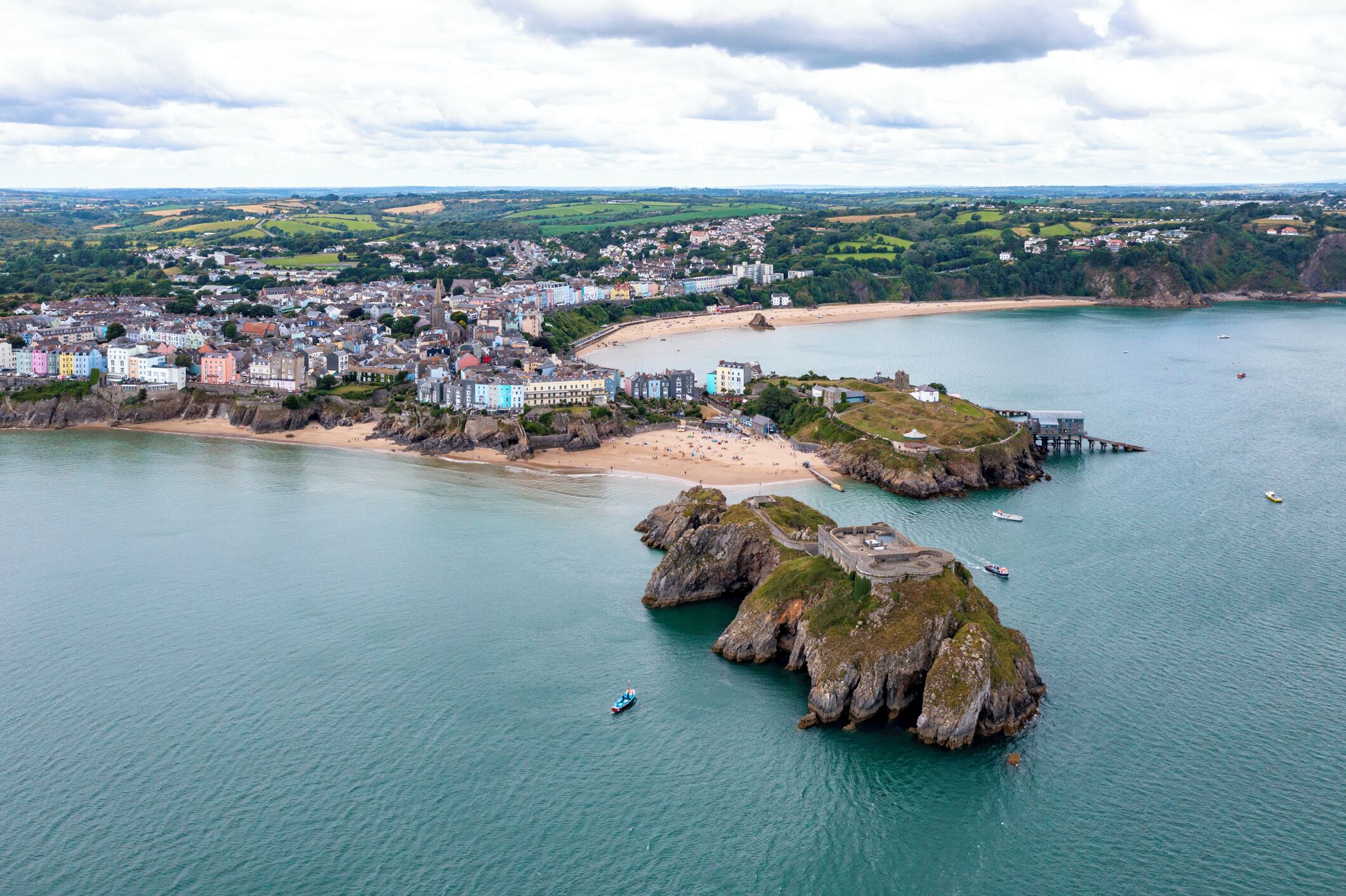 A coastal town with a beach, rocky outcrops, and a pier.
