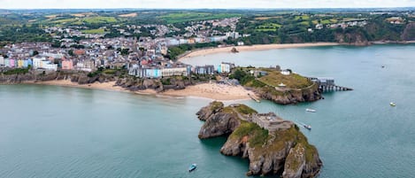 A coastal town with a beach, rocky outcrops, and a pier.