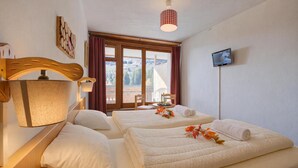 Een hotelkamer met twee bedden, een televisie, een raam met gordijnen en een lamp.