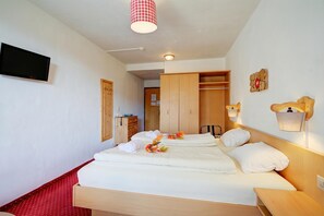 Een hotelkamer met een groot bed, een houten garderobe, een televisietoestel en een vloer met een rood patroon.