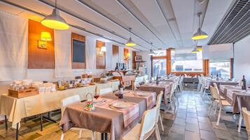 Ein Restaurant mit mehreren Essplätzen, jeweils mit Tellern, Besteck und Gläsern gedeckt.