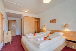 Habitación de hotel con dos camas, un armario de madera y una alfombra roja.