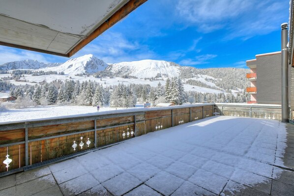 A snow-covered balcony with a view of a mountain range and a building with balconies. - Hotel Relais Grand Family Loft & Balcony1 120, Les Mosses, Switzerland (Les Mosses)