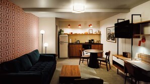 A compact living space with a sofa, a dining table, and a kitchen area. - La Vista Motel (Denver)