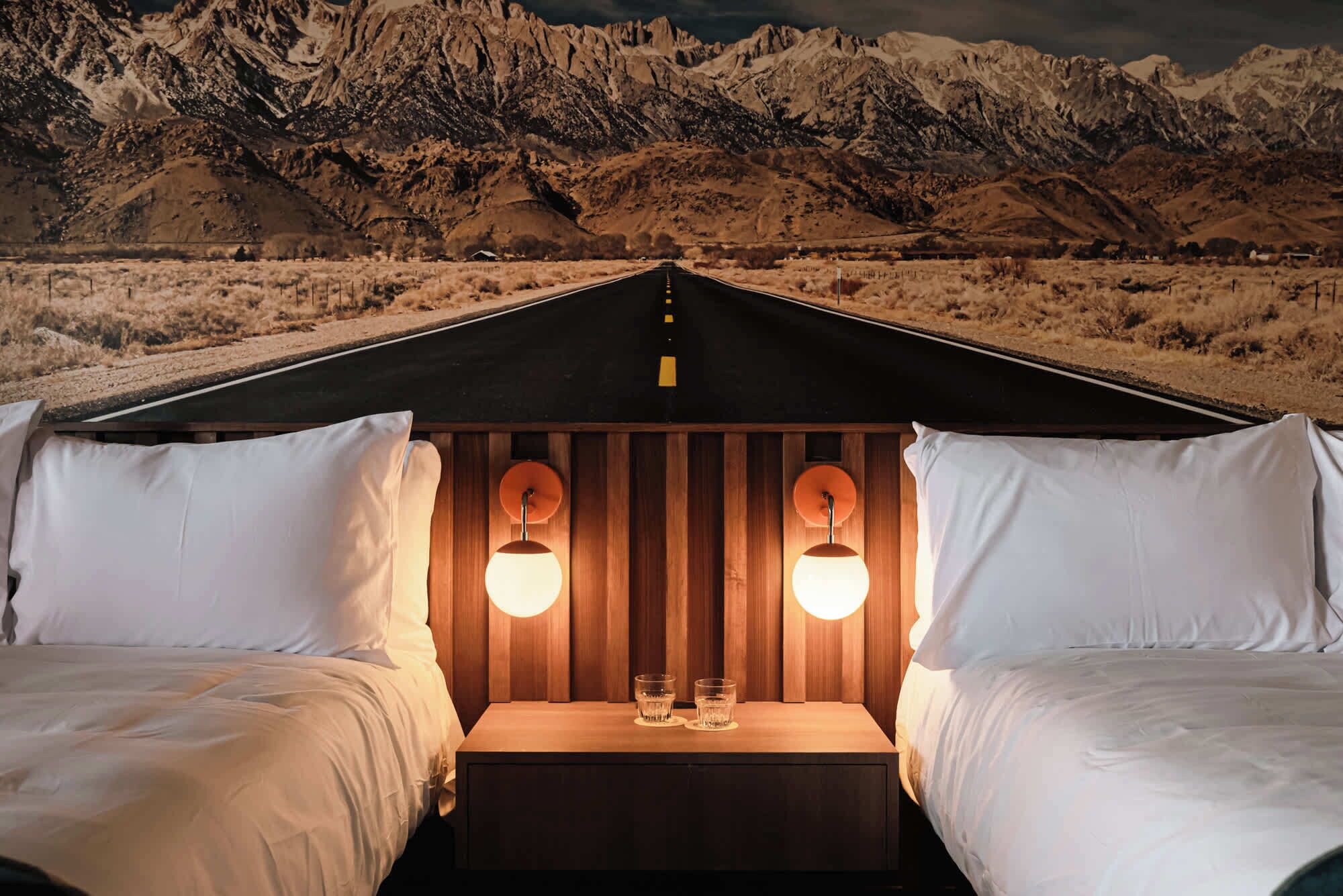 A tent with two beds, each with white bedding and two bedside lamps.