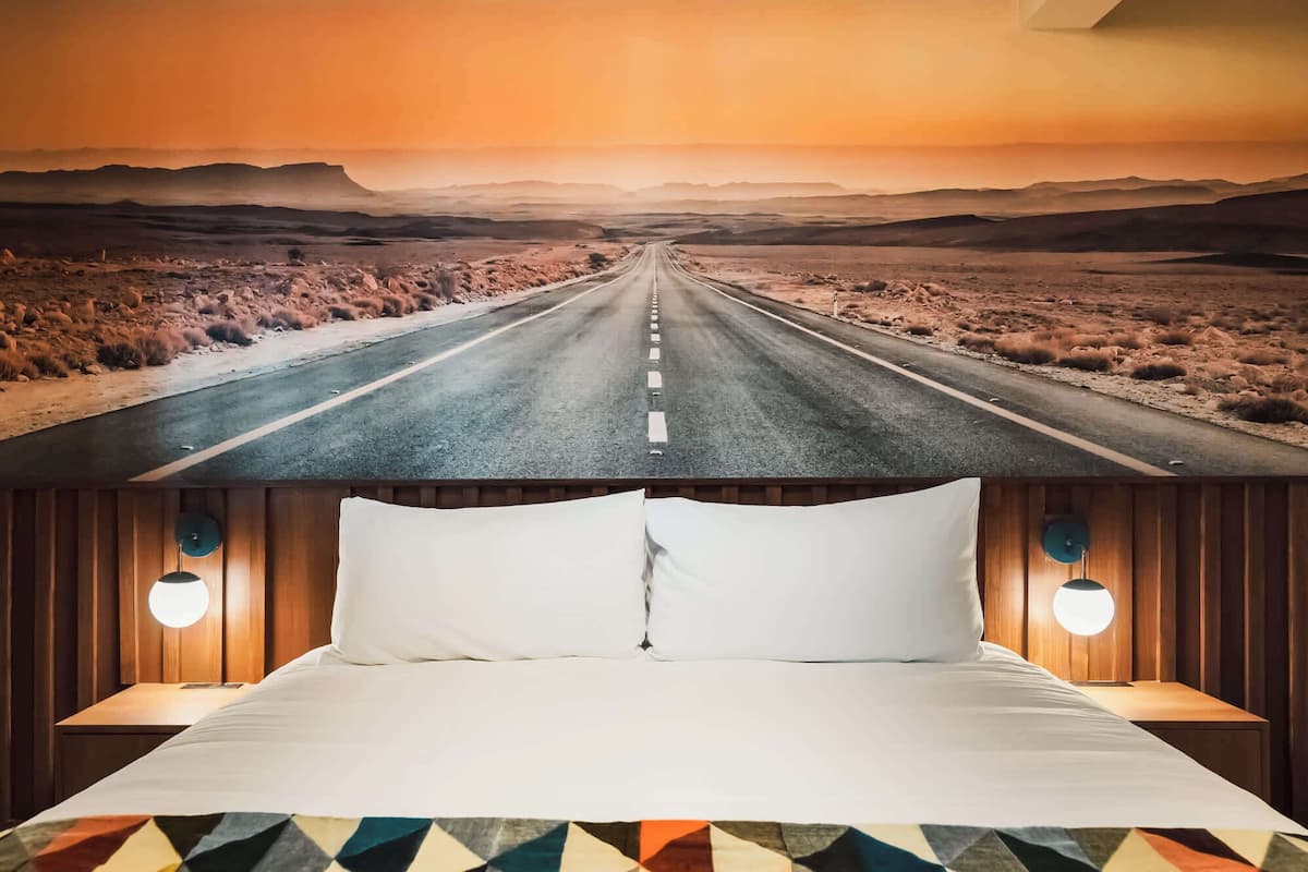 Una cama con vista a una carretera desértica a través de una ventana.