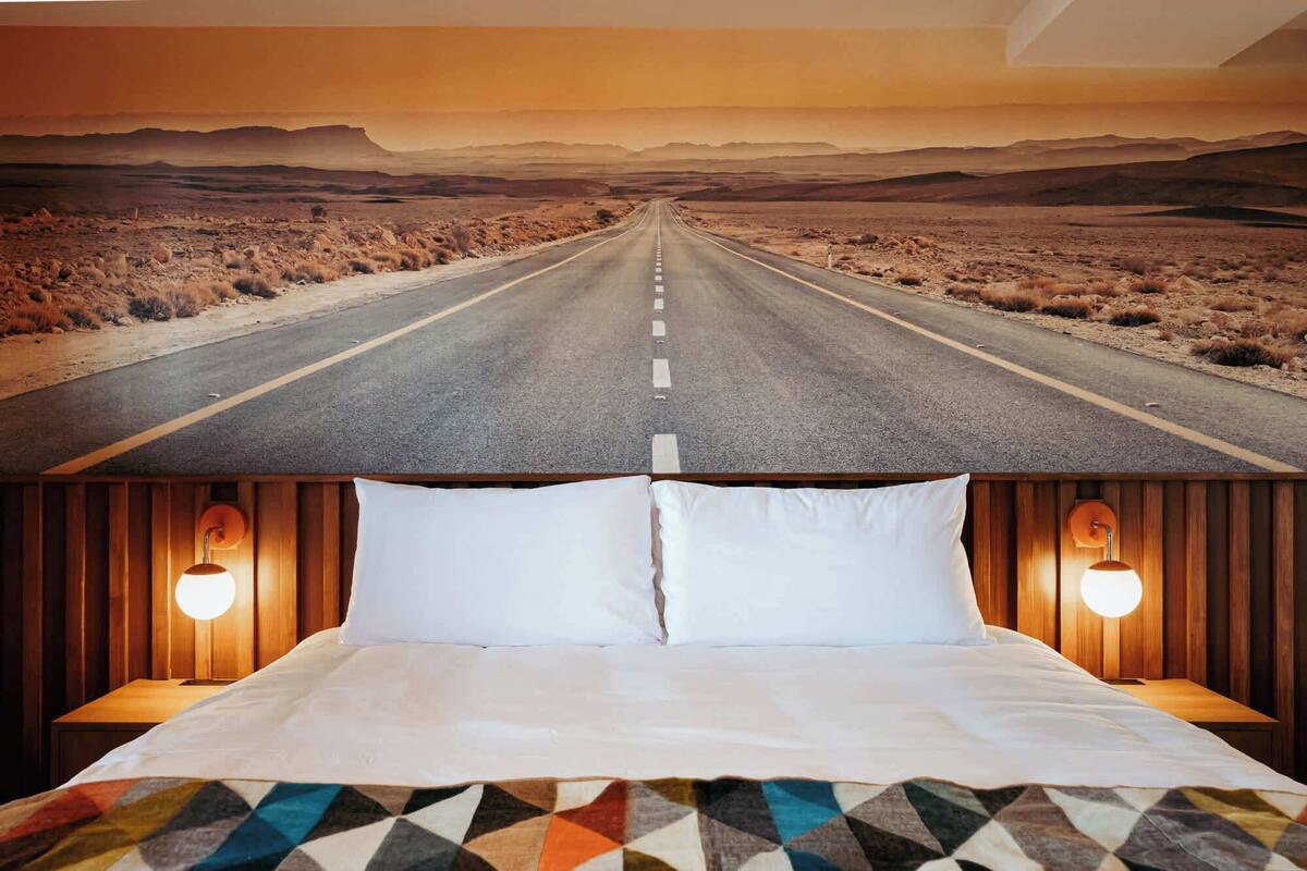 Una cama con vista a una carretera desértica a través de una ventana.