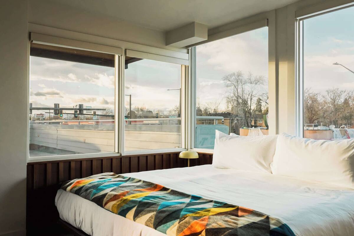Habitación de hotel con una cama grande, vista a una autopista y al paisaje urbano.
