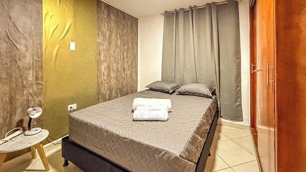 A bedroom with a bed, pillows, a bedside table, and a door. - Complete house 5 bedrooms | Laureles Co-Living (Medellín)