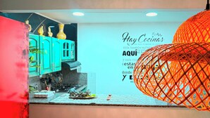 A kitchen with teal cabinets, a decorative orange hanging light, and a wall with a Spanish phrase. - Complete house 5 bedrooms | Laureles Co-Living (Medellín)