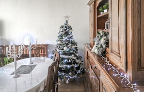 Ein Essbereich mit Weihnachtsbaum, weißem Tisch und Holzschrank.