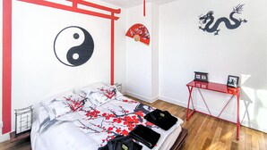 A bedroom with a bed, a desk, and a wall with a yin-yang symbol, a red fan, and a dragon.
