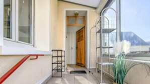 A balcony with a metal railing, a wooden door, and a tiled floor.