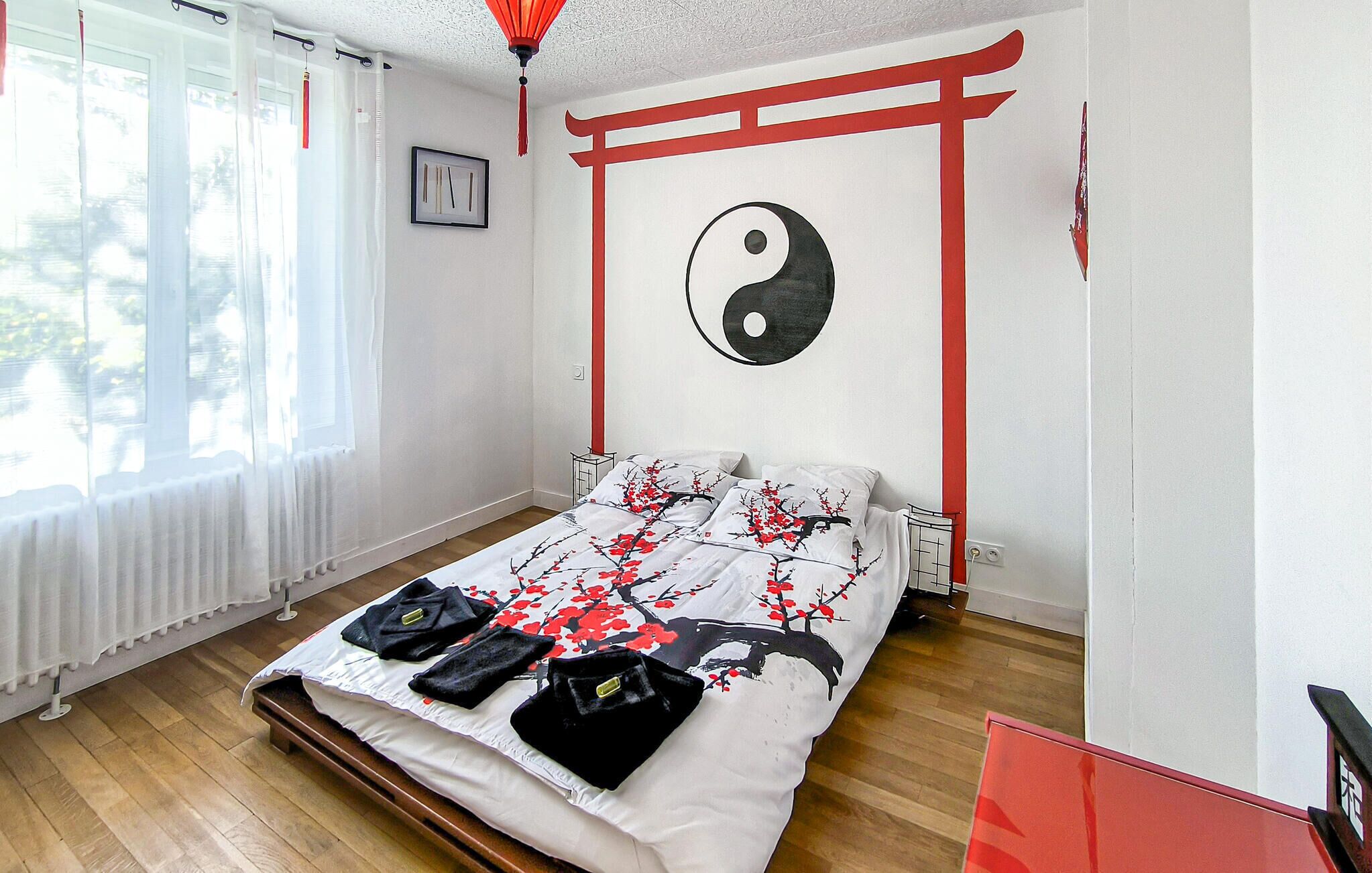 A bedroom with a bed, a window with curtains, a wall with a yin-yang symbol, and a red beam on the wall.