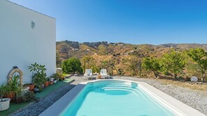 Ein Pool mit Blick auf Hügel, umgeben von Topfpflanzen und zwei Liegestühlen.