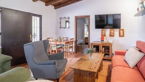 Ein Wohnzimmer mit Sofa, Sessel, Esstisch und Fernseher.