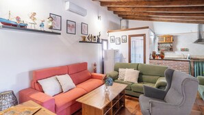 Ein Wohnzimmer mit einem roten Sofa, einem grünen Sofa und einem grauen Sessel. In der Mitte steht ein Holztisch.