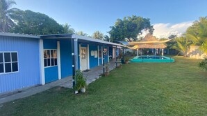 A row of blue buildings with a swimming pool and a thatched-roof structure in the background. - 3-bedroom house in PLAYA LAS HOJAS , SAN PEDRO ,MASAHUAT DPT LA PAZ. (san pedro masahuat)