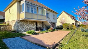 Una casa a due piani con fondamenta in pietra, un portico anteriore e un vialetto sterrato.