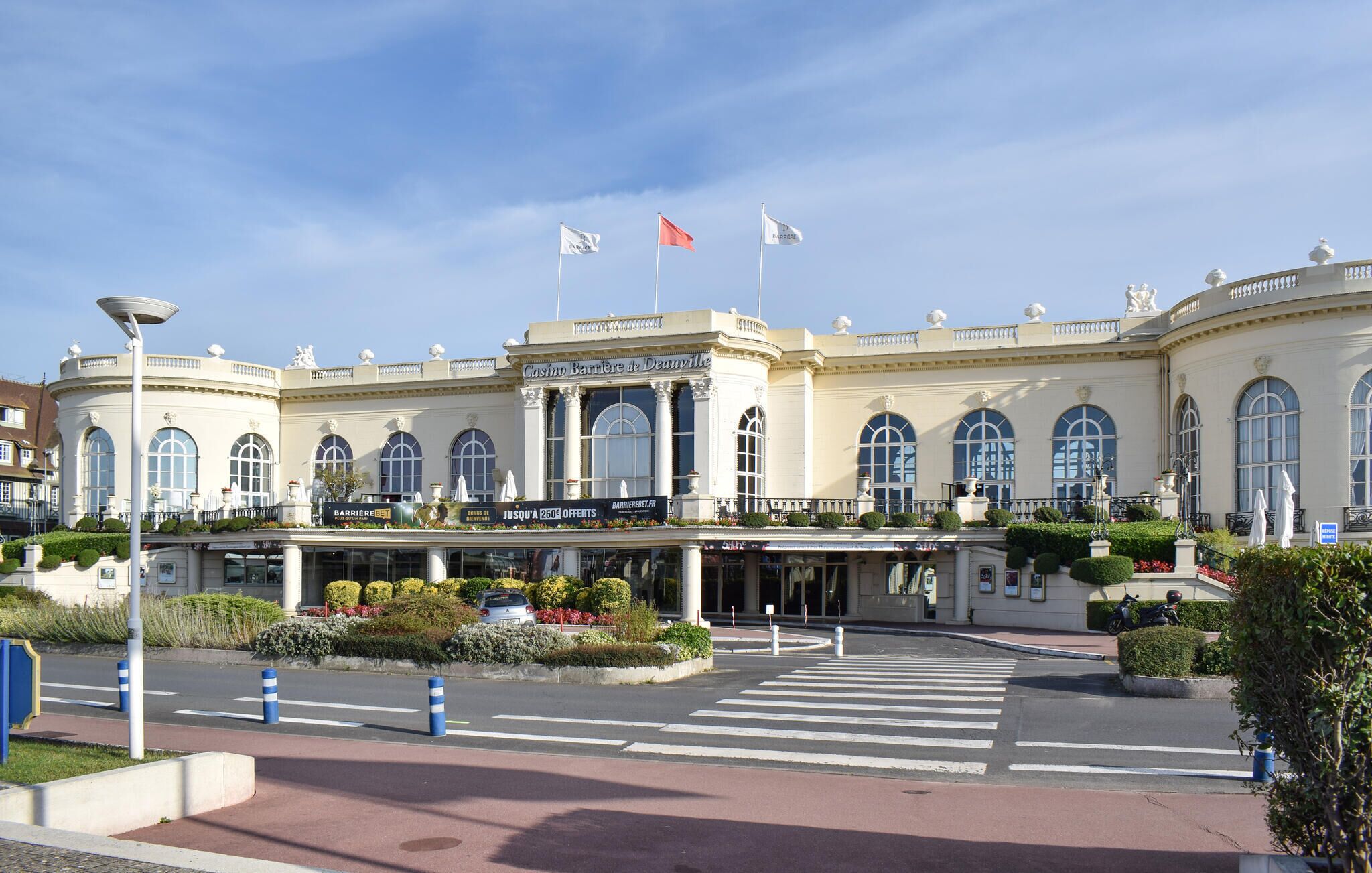 Un imposant bâtiment de style architectural classique, doté d’une entrée remarquable surmontée d’un auvent, de grandes fenêtres en arc de cercle et d’un mât central.