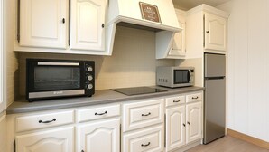 Una cucina con mobili bianchi, un forno Bosch, un forno a microonde e un frigorifero in acciaio inossidabile.