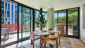 A modern dining area with a round table, chairs, and a large plant. - Sage Zen Muse Docklands Retreat (Docklands)