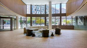A spacious lobby with a central seating area, large windows, and a view of the cityscape. - Sage Zen Muse Docklands Retreat (Docklands)
