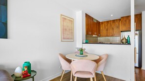 Una cocina moderna con armarios de madera, una mesa redonda con dos sillas y una mesita auxiliar con adornos.