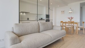 Una sala de estar moderna con sofá, una mesa de comedor con sillas, una zona de cocina y un espejo grande.