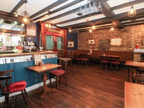 A restaurant interior with wooden tables and chairs, a bar area, and a stone wall. - Black Bull No.3 (Bishop Auckland)